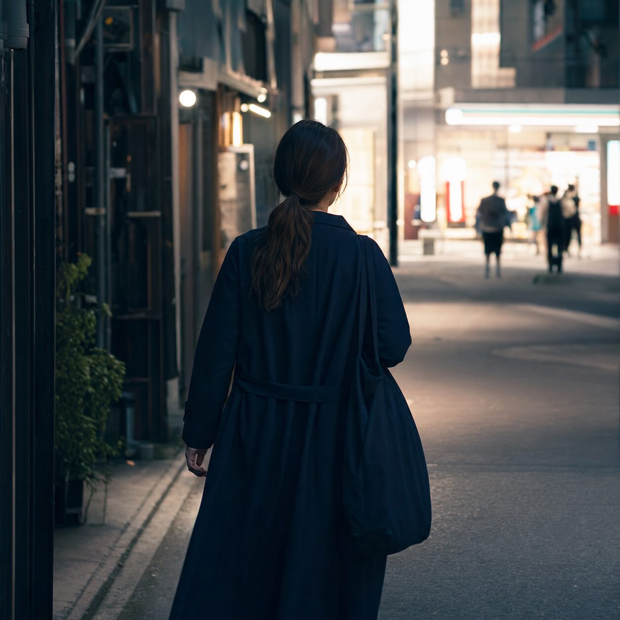 暗い路地を離れて明るい通りへ向かう成人女性